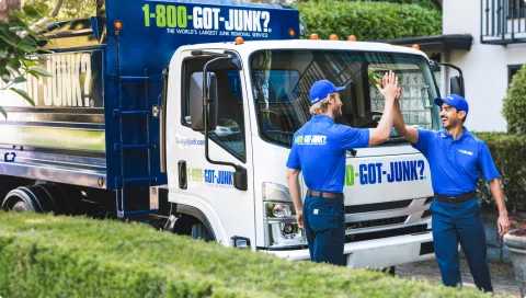 1-800-GOT-JUNK? team members high-fiving in front of junk removal truck
