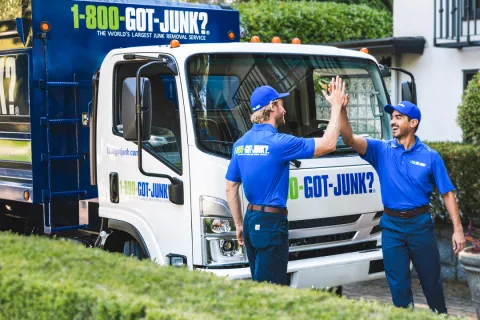 1-800-GOT-JUNK? team members high-fiving in front of junk removal truck