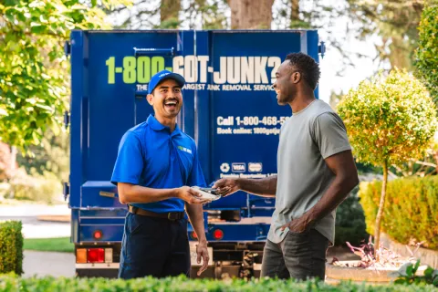 1-800-GOT-JUNK junk removal expert getting payment from happy customer outside