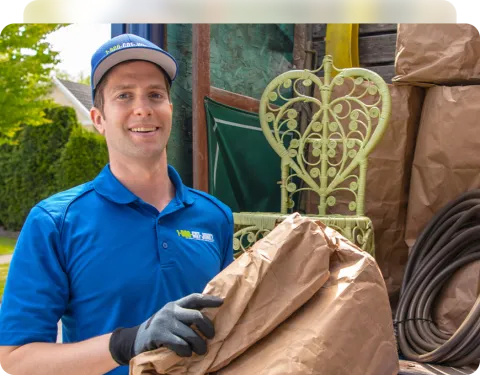 1-800-GOT-JUNK? employee posing by junk removal truck holding brown paper bag