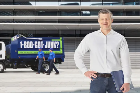 happy property manager in front of team members removing junk